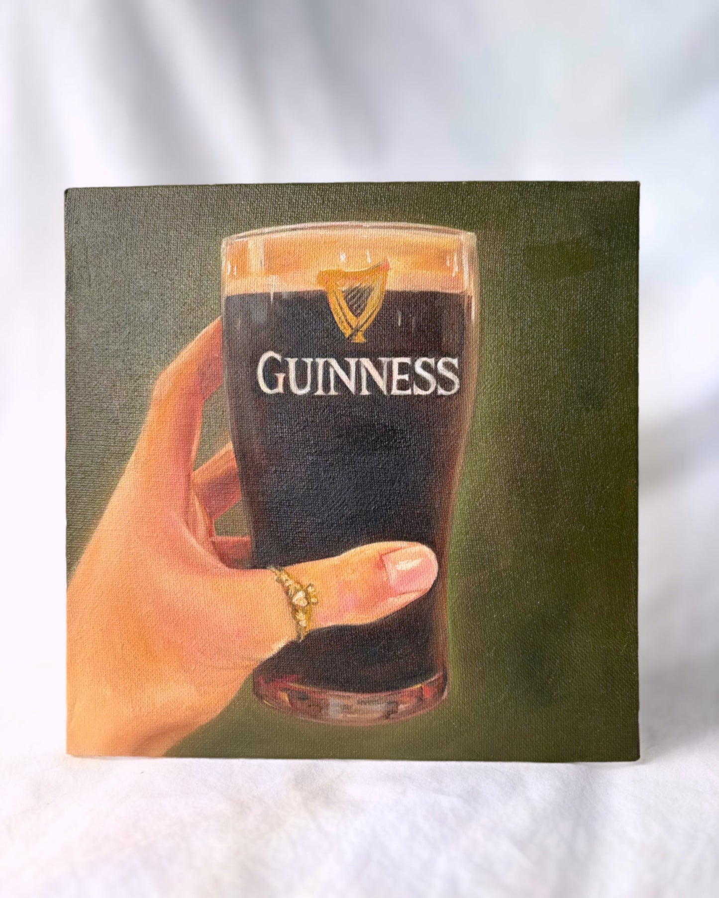 Hand holding a glass of Guinness beer with a green background
